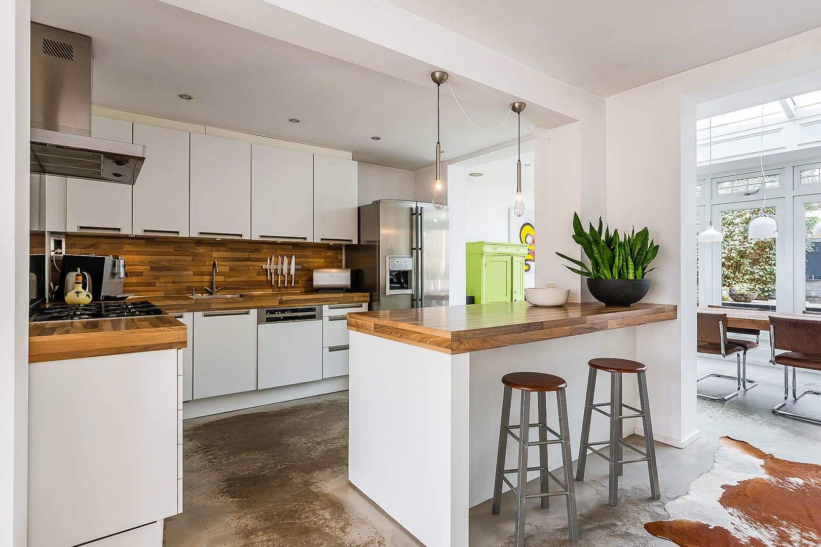 Witte open keuken met houten werkblad en barkrukken